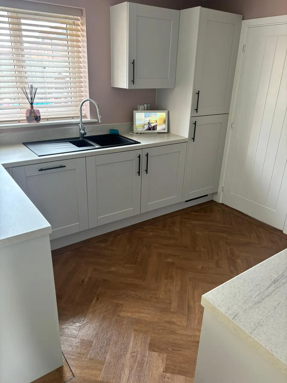 Clean residential kitchen with detailed cabinetry, worktops, sink and hard flooring