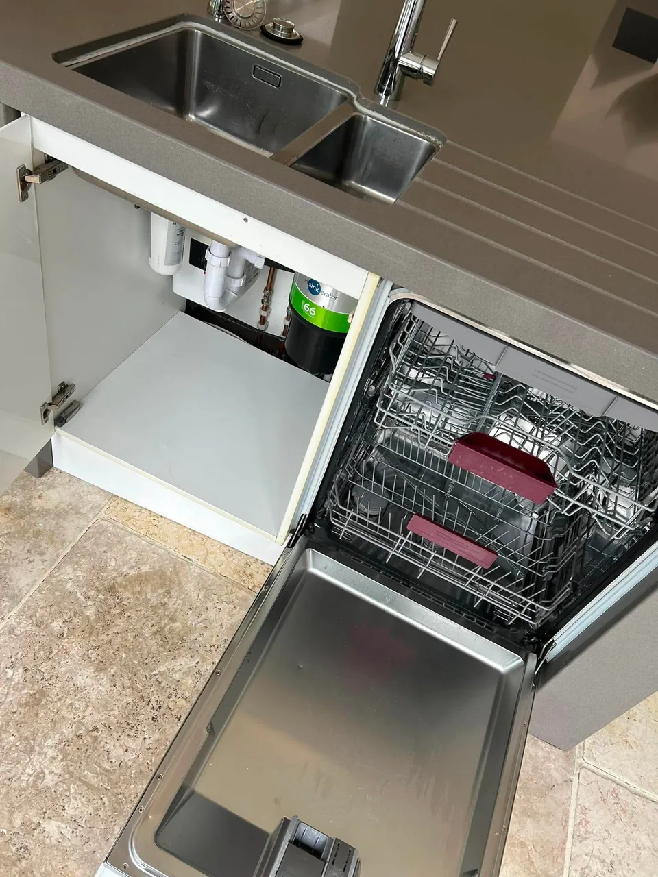 Detailed cleaning within a domestic kitchen dishwasher and surrounding cupboard
