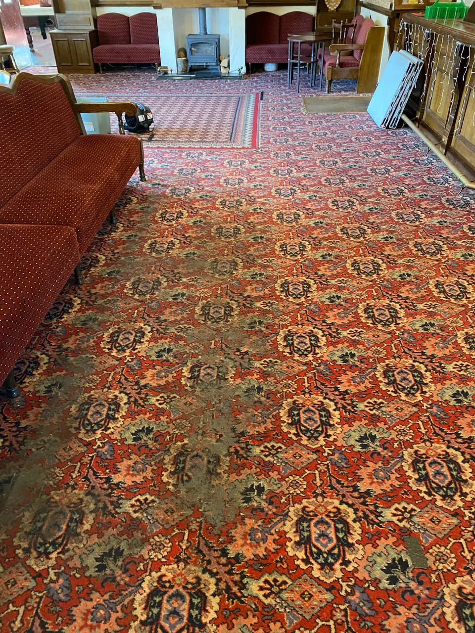 Commercial pub lounge with patterned carpet and cleaning equipment visible