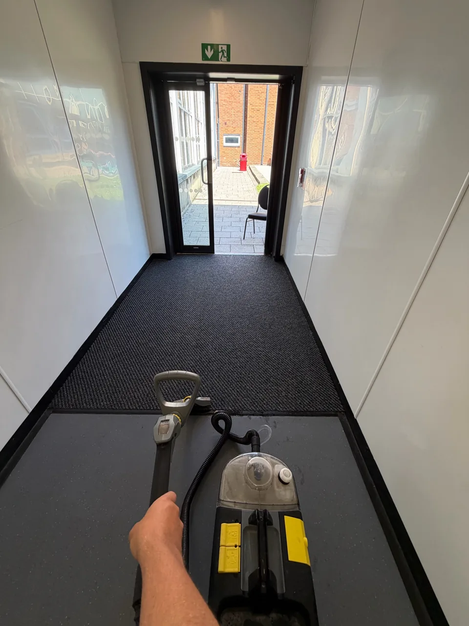 Commercial carpet-cleaning equipment being used across a school corridor