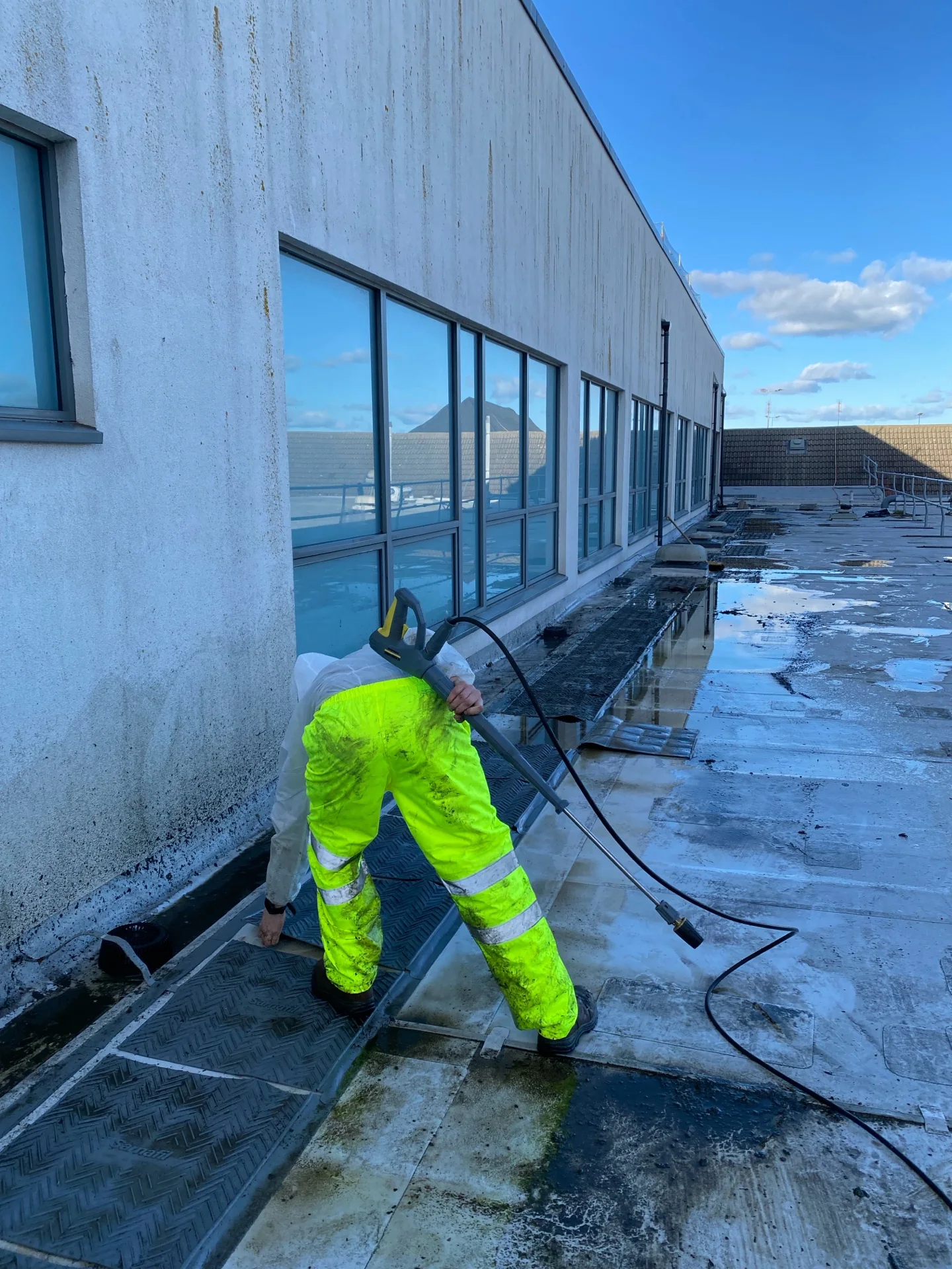 Active roof-cleaning work at a school roof-and-gully project